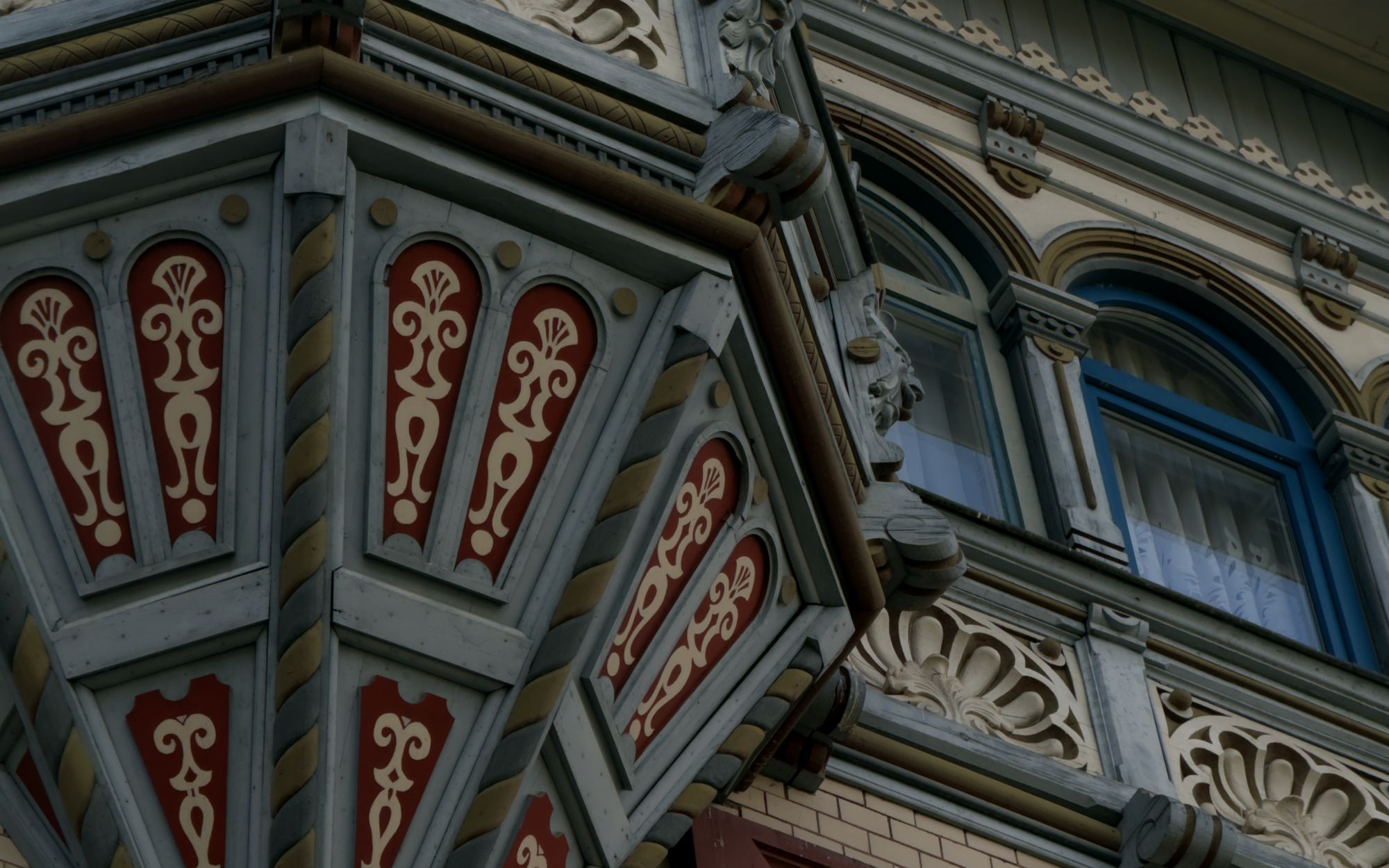 Verzierter Erker an der Fassade der Krone mit roten Ornamenten und blauen Fenstern